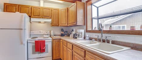 Una cocina con armarios de madera, un refrigerador blanco, una estufa y un lavabo.