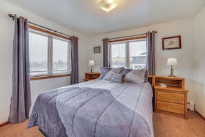 A bedroom with a bed, two bedside tables, a nightstand, a lamp, and a window with curtains. - Cozy Anchorage Vacation Rental Near Hospitals! (Anchorage)