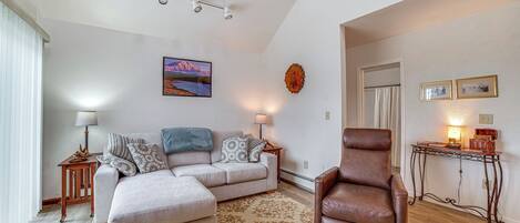 A living room with a sofa, armchair, and a small table with a lamp.