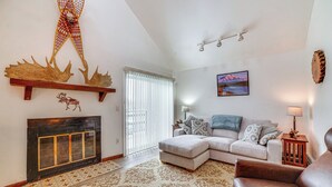 A living room with a fireplace, a sofa, a coffee table, and a decorative wall hanging. - Cozy Anchorage Vacation Rental Near Hospitals! (Anchorage)