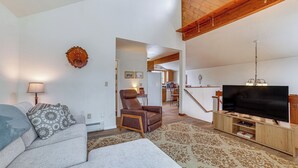 A living room with a sofa, armchair, and a TV on a wooden stand. - Cozy Anchorage Vacation Rental Near Hospitals! (Anchorage)