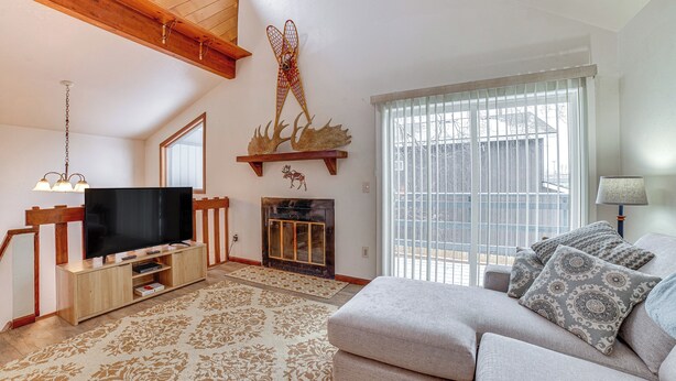 A living room with a flat-screen TV, wooden entertainment unit, patterned rug, and a fireplace. - Cozy Anchorage Vacation Rental Near Hospitals! (Anchorage)
