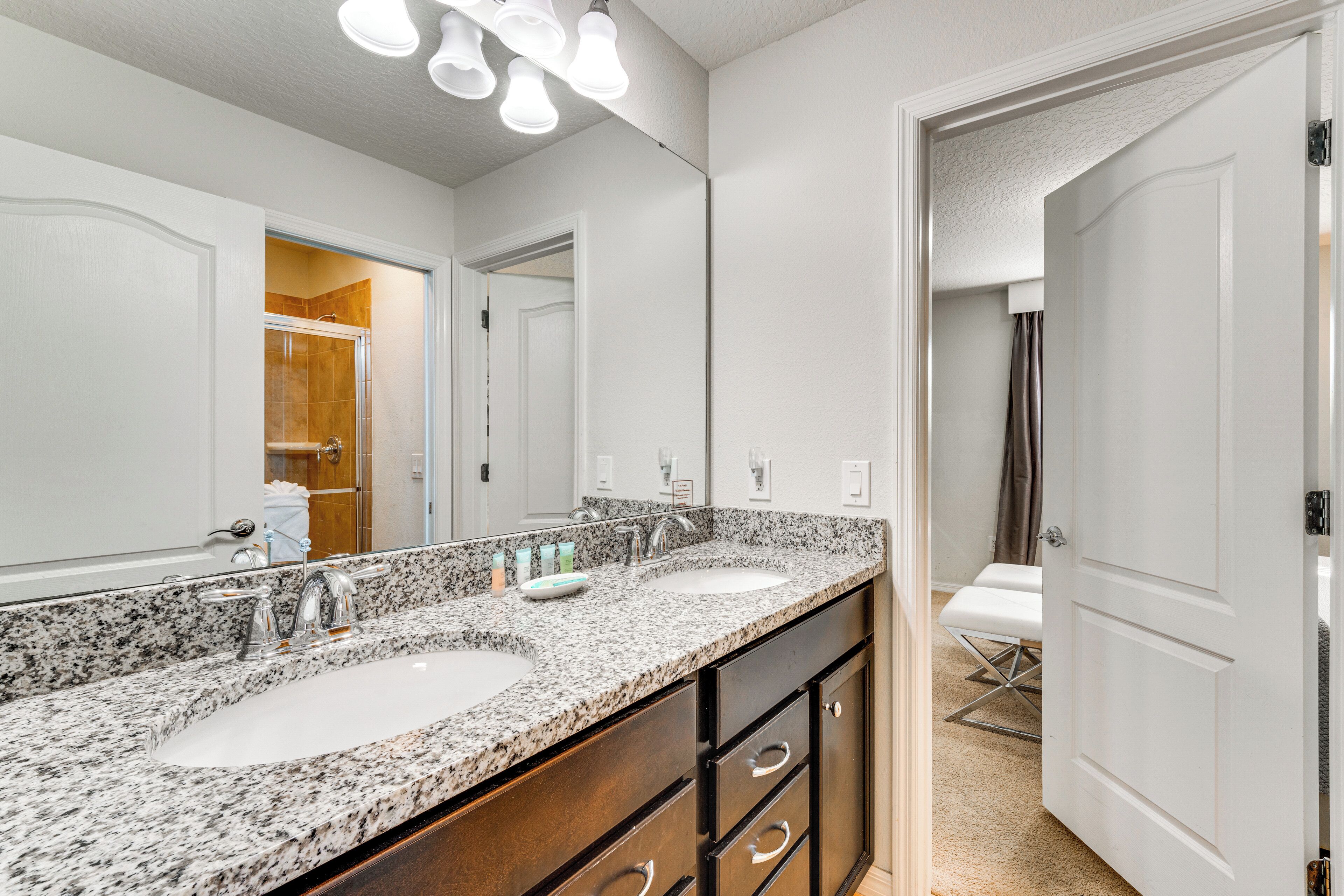 A bathroom with a granite countertop, double sink, and a large mirror.
