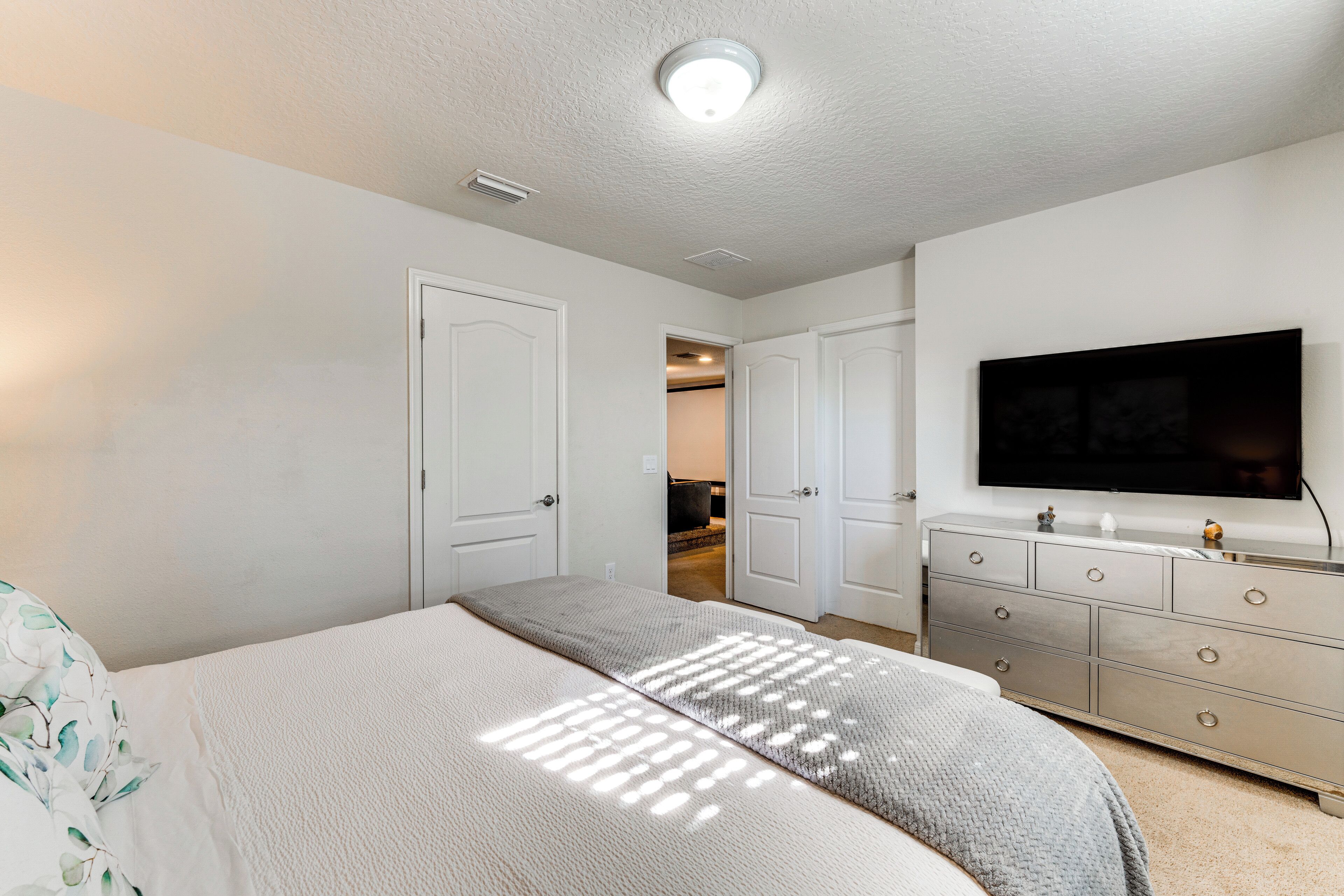 A bedroom with a bed, a dresser, a television, and a closet.
