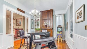 A dining area with a wooden table, two chairs, and a chandelier.
