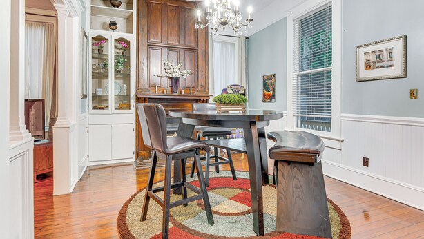 A dining area with a round table, chairs, and a chandelier.