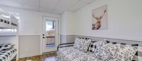 A bedroom with a bed, a window, a door, and a wall-mounted deer painting.