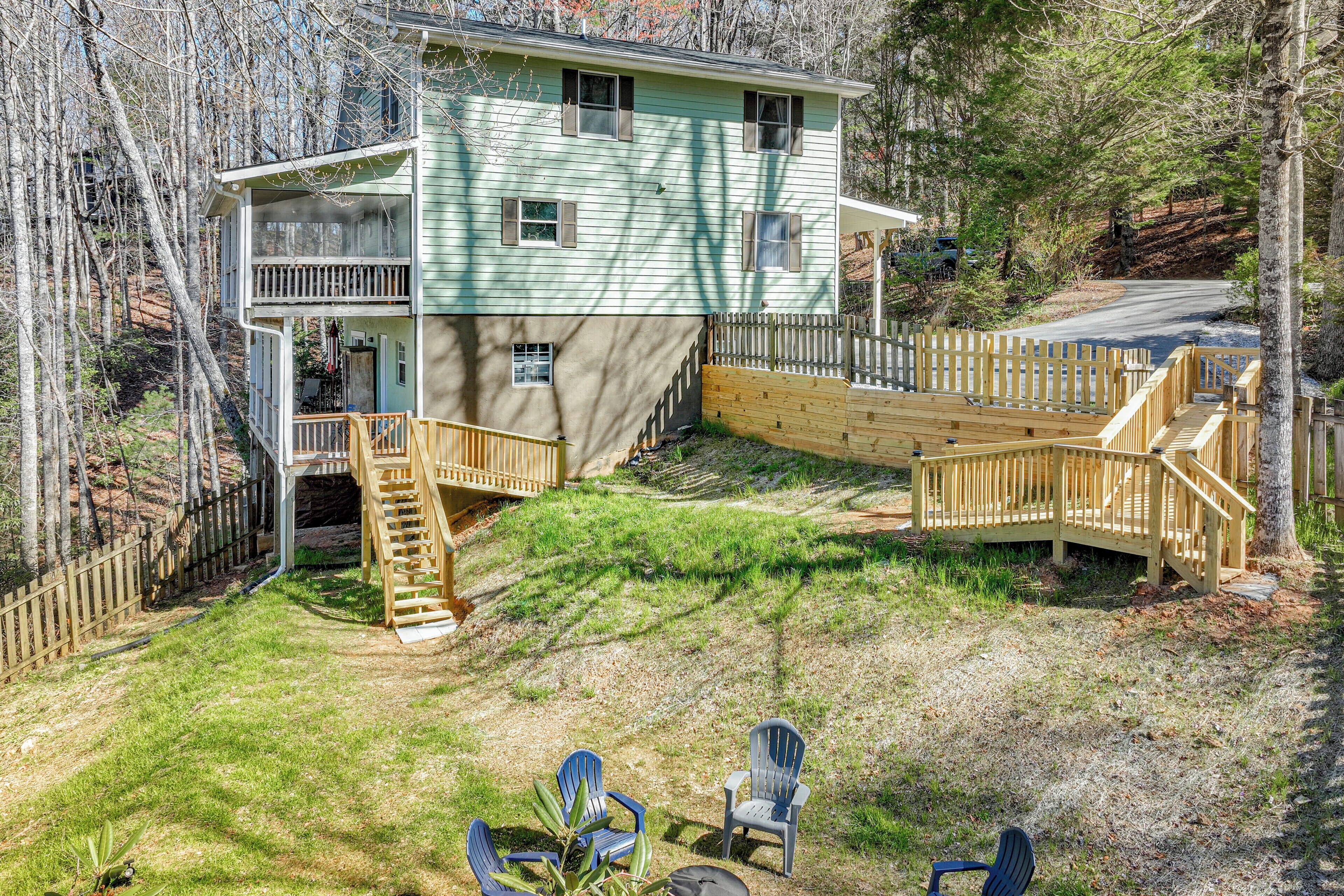 Ein zweistöckiges Haus mit Terrasse, Treppe und einem eingezäunten Garten mit Stühlen.