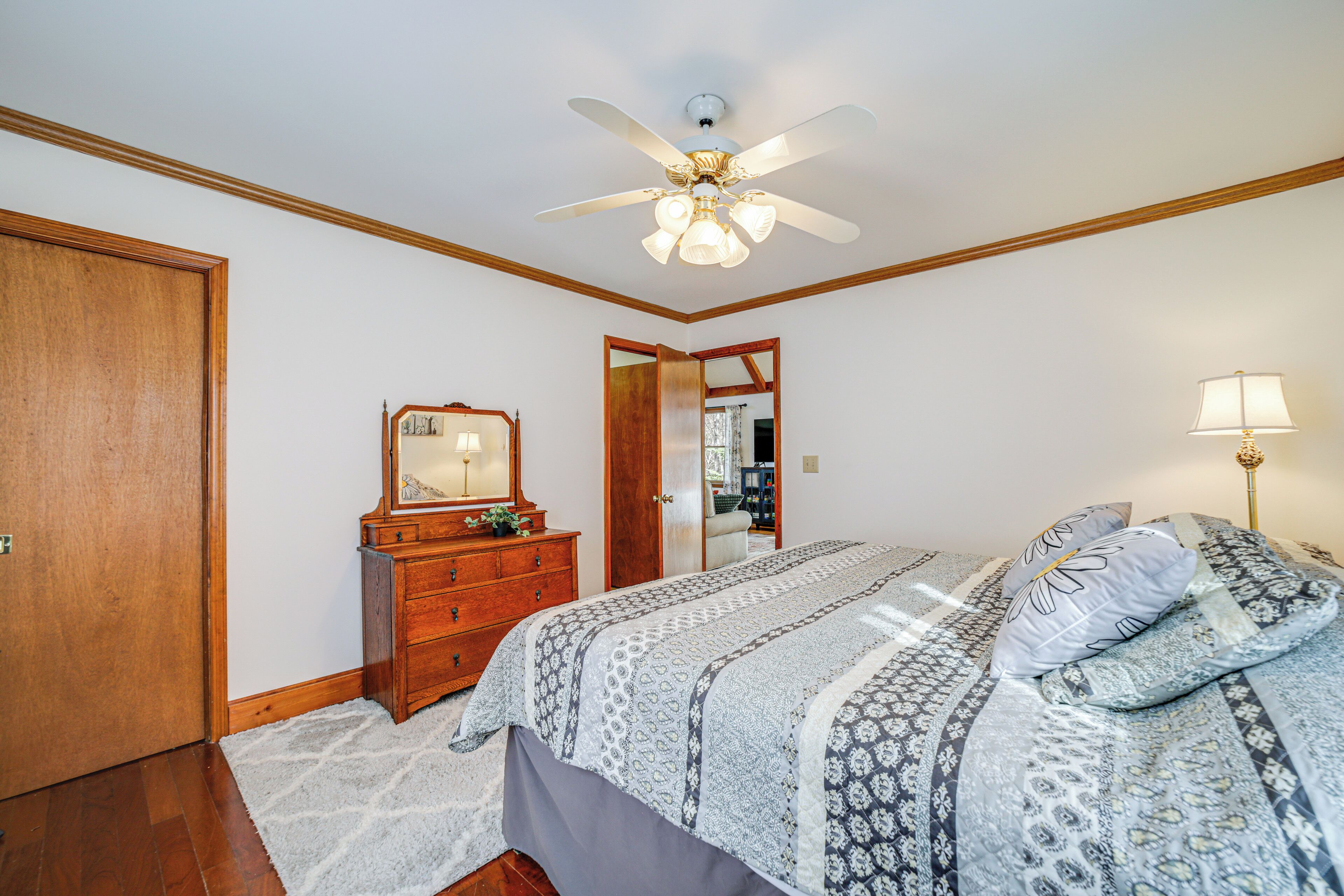A bedroom with a bed, a dresser, a mirror, and a ceiling fan.