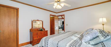 A bedroom with a bed, a dresser, a mirror, and a ceiling fan.
