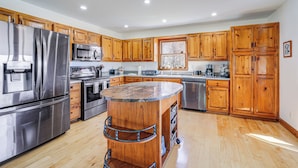 A modern kitchen with wooden cabinets, stainless steel appliances, and a central island. - Sky Valley Retreat w/ Fire Pit & Mountain Views! (Dillard)