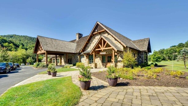 A stone building with a pitched roof and wooden beams, surrounded by a well-maintained lawn and potted plants. - Sky Valley Retreat w/ Fire Pit & Mountain Views! (Dillard)