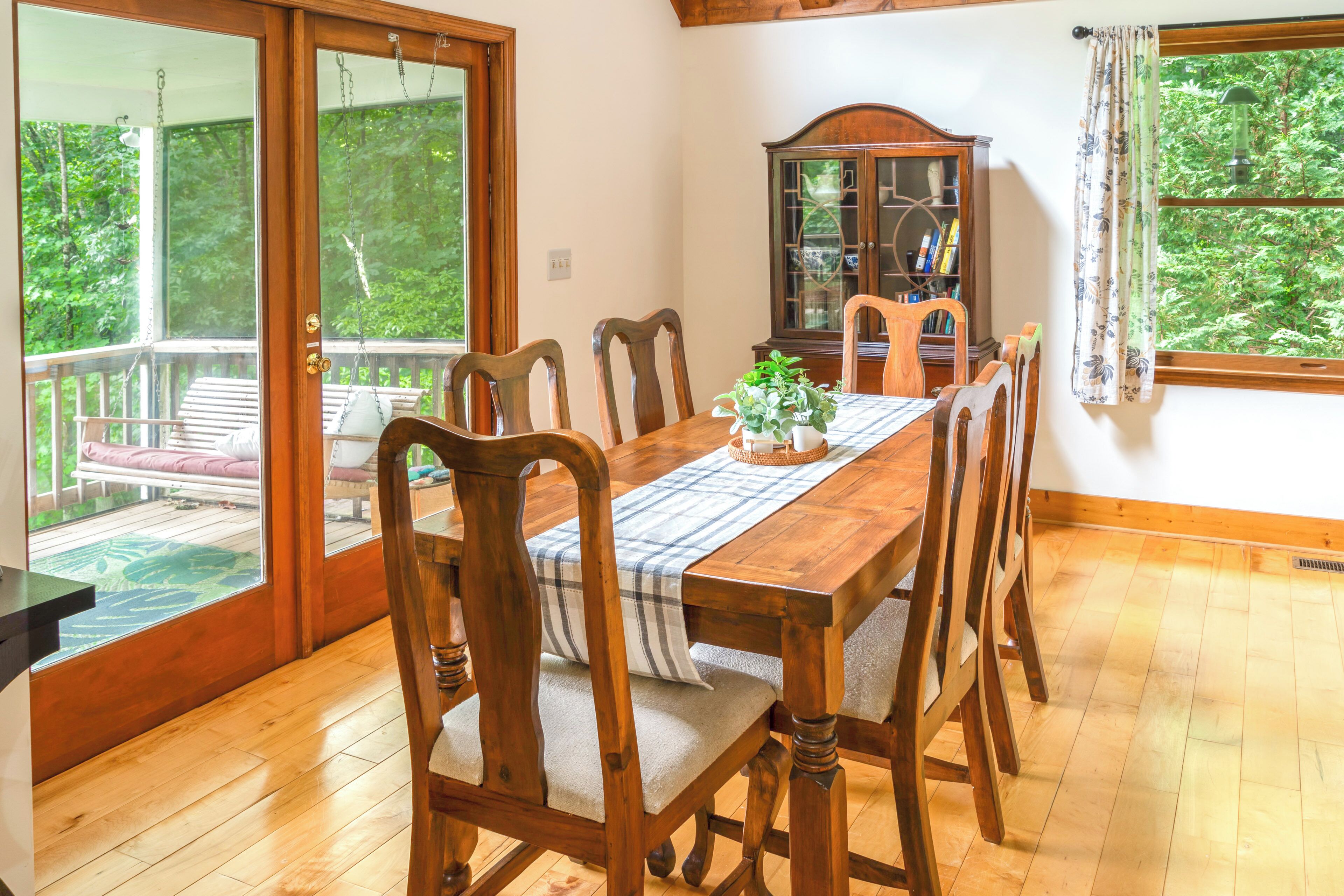 A dining area with a wooden table, chairs, and a bench outside.