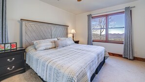 A bedroom with a large bed, a nightstand, a ceiling fan, and a window with curtains. - Sky Valley Retreat w/ Fire Pit & Mountain Views! (Dillard)