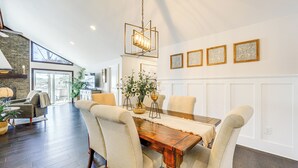 A dining area with a wooden table, beige upholstered chairs, and a hanging light fixture.