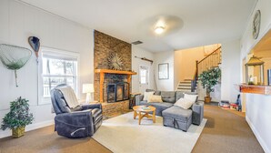 A cozy living room with a fireplace, a staircase, and a small Christmas tree.