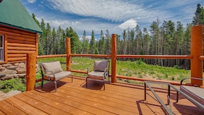 Une terrasse en bois avec deux chaises et une vue sur une forêt.
