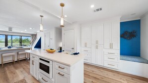A modern kitchen with white cabinetry, a central island, and pendant lighting. - 30a Hideaway 2 Bedroom Townhouse by RedAwning (Panama City Beach)