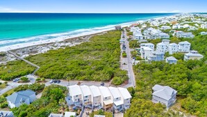 An aerial view of a coastal residential area with beachfront properties, a road, and dense greenery. - 30a Hideaway 2 Bedroom Townhouse by RedAwning (Panama City Beach)