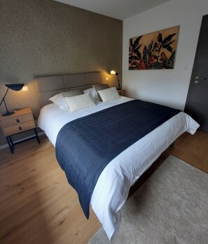 Ein Schlafzimmer mit einem Bett, Nachttischen, einer Lampe und einem Wandbild.