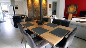Un espace de salle à manger moderne avec une table en bois et des chaises à revêtement gris, un mur d’accent rouge et une cheminée.