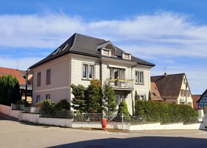 Ein zweistöckiges Haus mit Balkon, Auffahrt und gepflegtem Rasen.