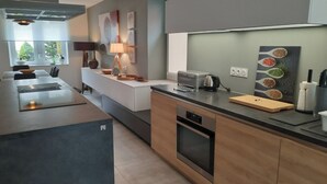Une cuisine moderne dotée d’un îlot central, d’un four encastré et d’un coin repas avec une table et des chaises.