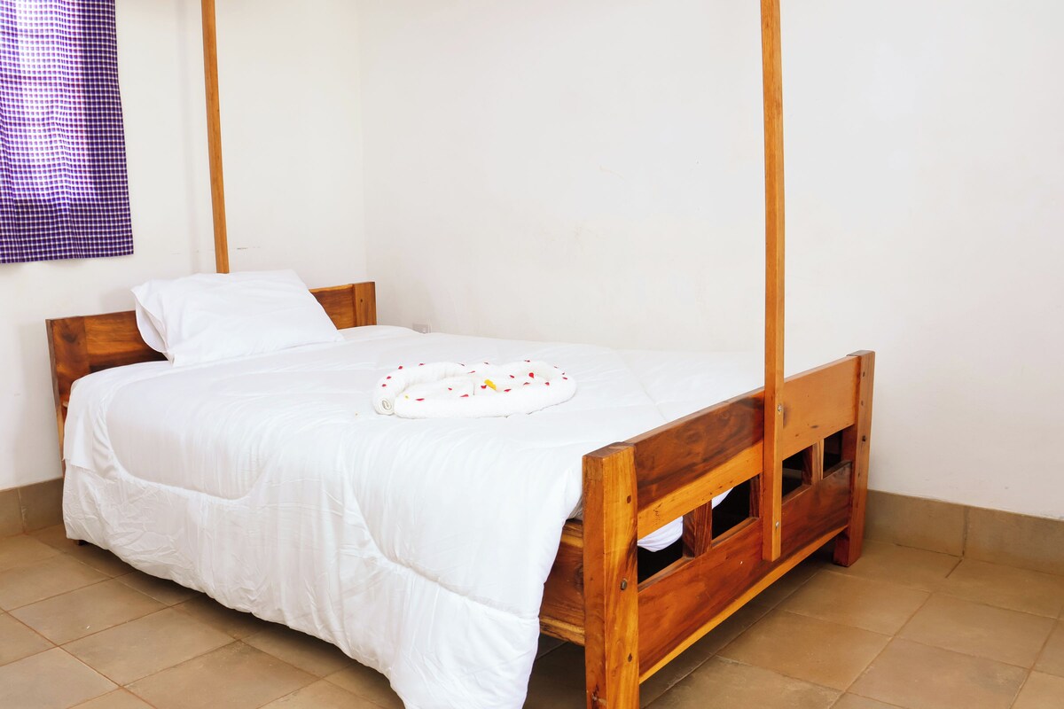 A single bed with a wooden frame, white bedding, and a circular object on the bed.