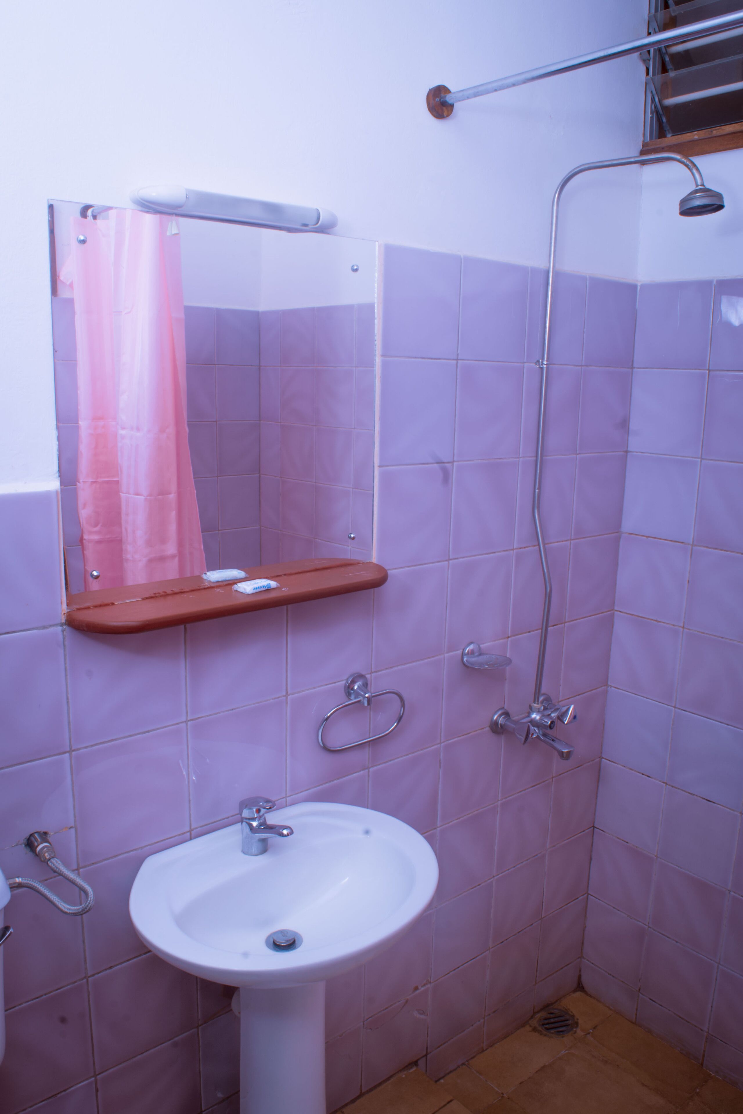 Un baño con lavamanos, espejo, ducha y toallero.