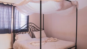 A four-poster bed with a canopy, white bedding, and a window with a checkered curtain. - Stc.Safari lodge (Karatu)