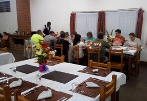 A restaurant with multiple tables set for dining, featuring wooden chairs and white tablecloths. - Stc.Safari lodge (Karatu)
