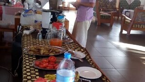 A dining table set with plates, a water bottle, and a bowl of salad. - Stc.Safari lodge (Karatu)