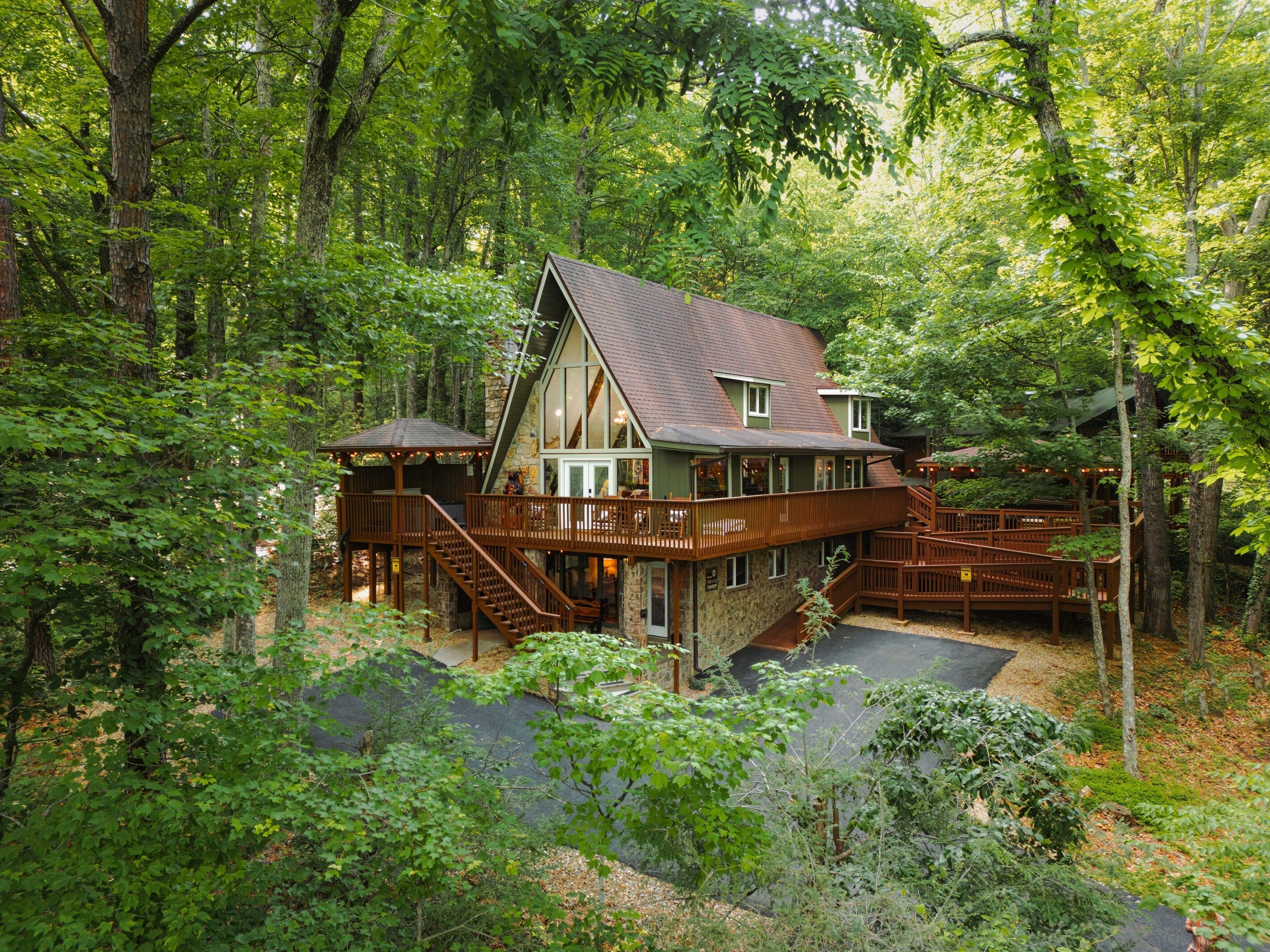 A lodge with a stone foundation, wooden deck, and multiple levels connected by stairs.