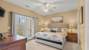 A bedroom with a bed, bedside lamps, a ceiling fan, a desk, and a large window with curtains. - Short Stays in Summer - Pool - Seven Oaks 9-302 (North Myrtle Beach)