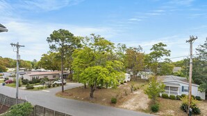 A residential street with houses, a clear sky, and a fenced area. - Short Stays in Summer - Pool - Seven Oaks 9-302 (North Myrtle Beach)