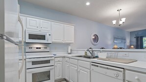 A modern kitchen with white cabinetry, a built-in microwave, oven, and dishwasher. - Short Stays in Summer - Pool - Seven Oaks 9-302 (North Myrtle Beach)