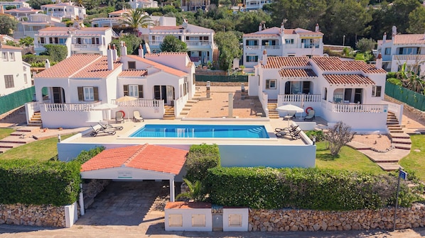 A residential area with multiple houses, a swimming pool, and a stone wall.
