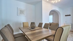 A dining area with a wooden table and six chairs, a decorative centerpiece, and a ceiling light fixture.