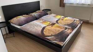 A bed with a black headboard and a patterned bedspread. There are two bedside tables, one on each side of the bed. - Malý Janek z Jinec - brewery (Jince)