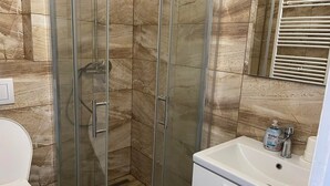 A bathroom with a glass-enclosed shower, a white sink, and a mirror above the sink. - Malý Janek z Jinec - brewery (Jince)