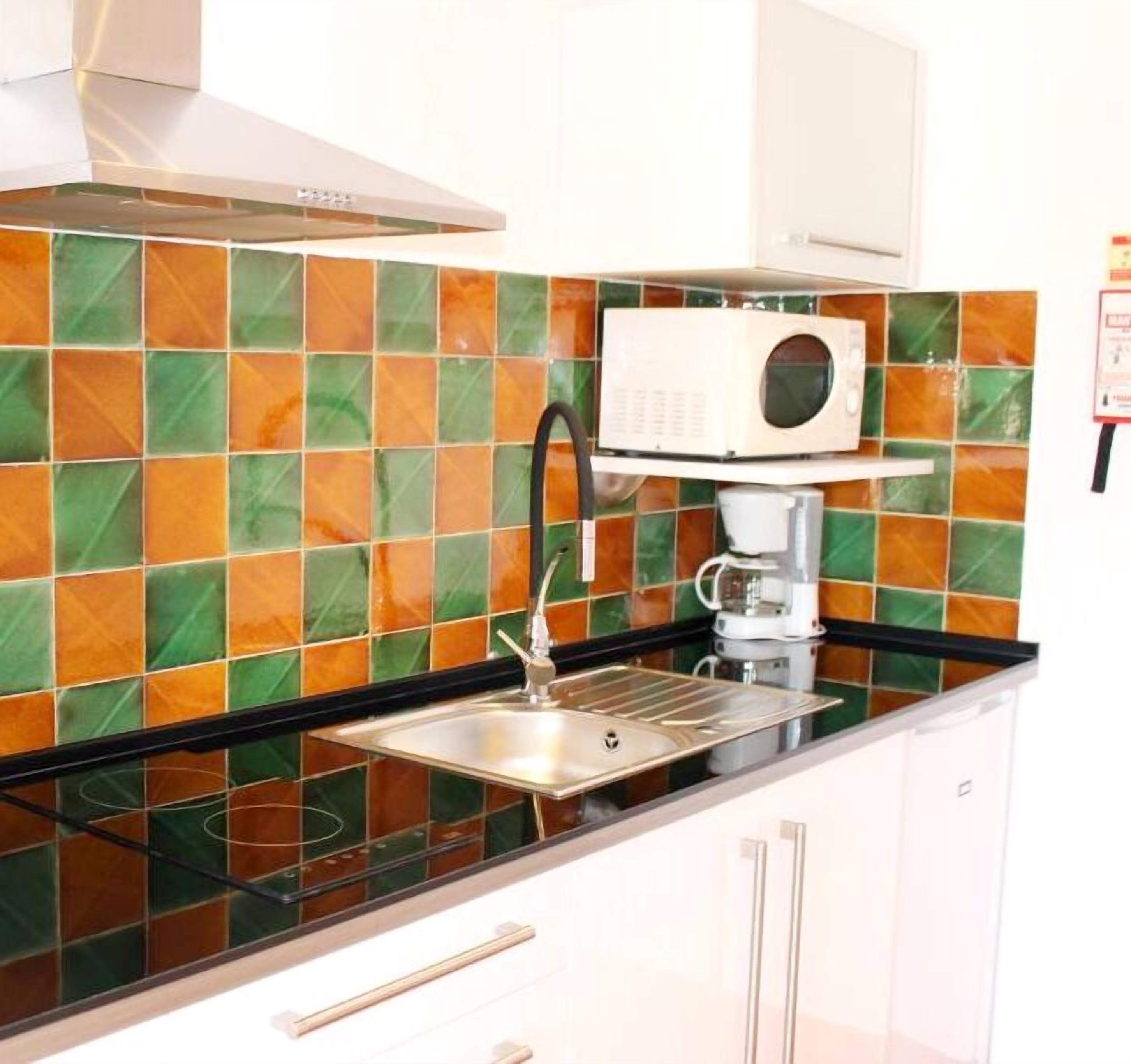 A kitchen with a stainless steel sink, a coffee machine, and a microwave.