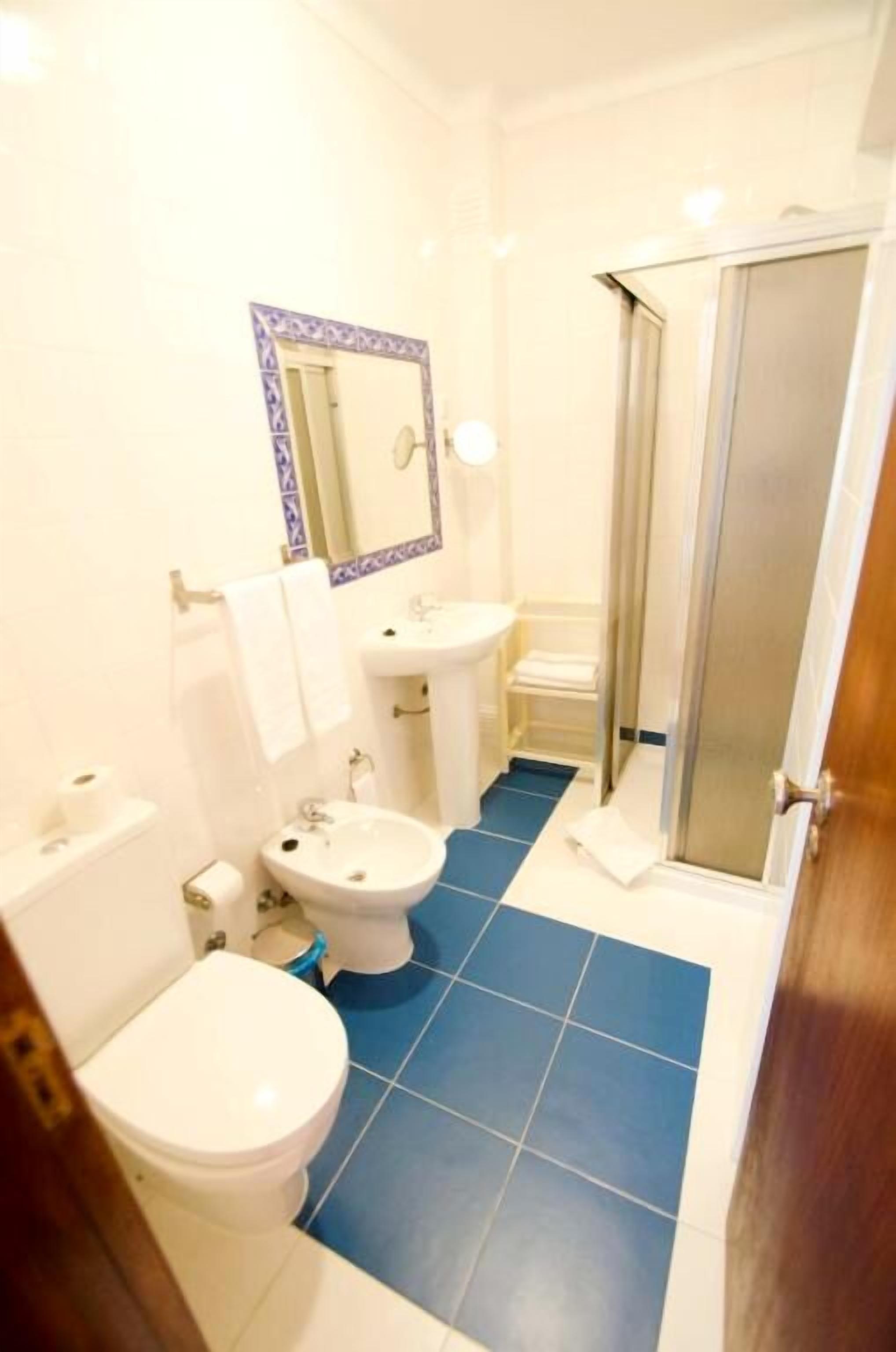 Un baño con inodoro, bidé, lavabo y zona de ducha.