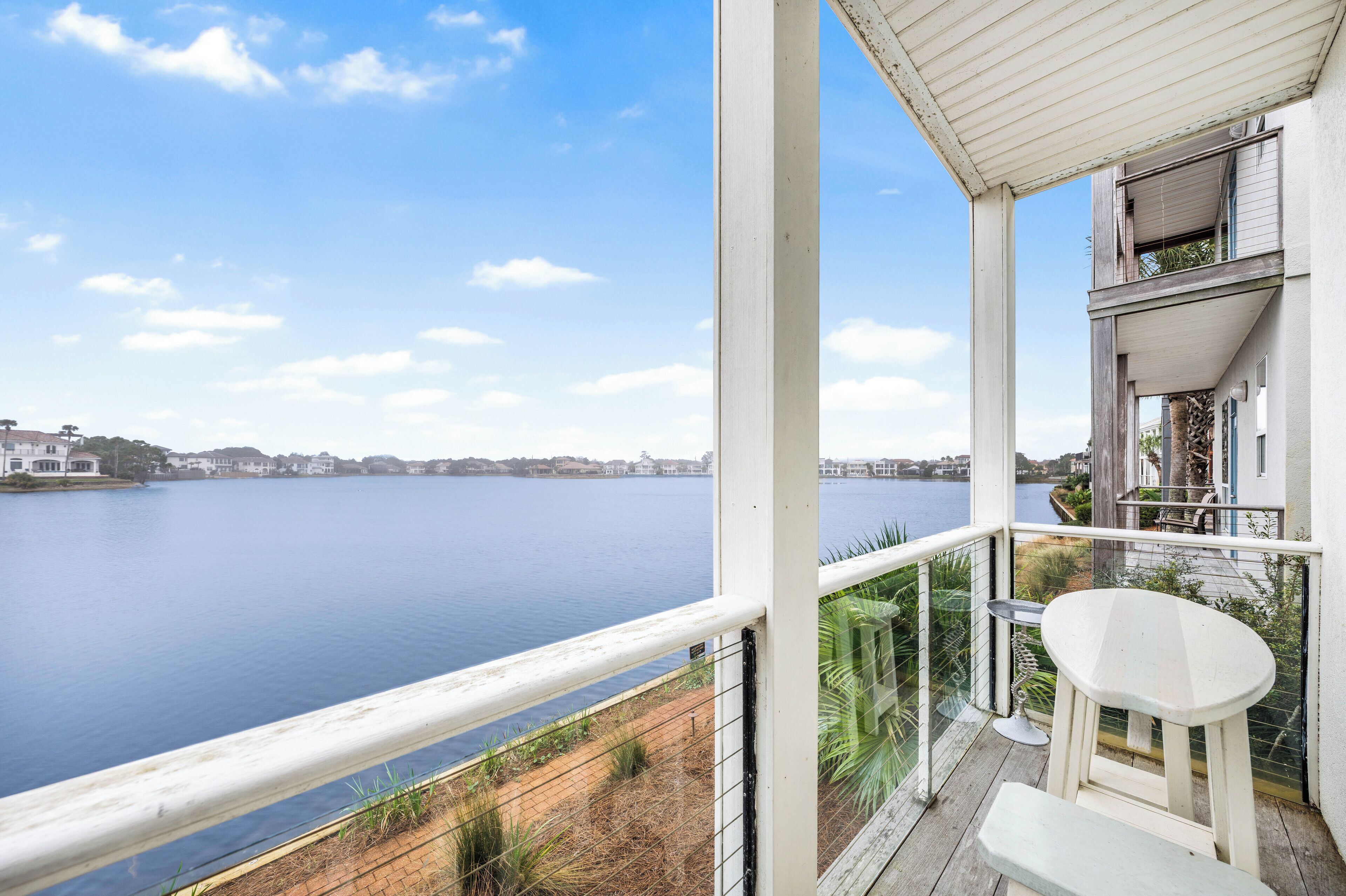 Een balkon met uitzicht op een rustig meer en verre gebouwen.