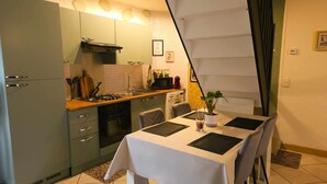 A compact kitchen with a dining area, featuring a stove, sink, and cabinets. - Maison en Centre-ville Avec Jardin Privatif (Nevers)