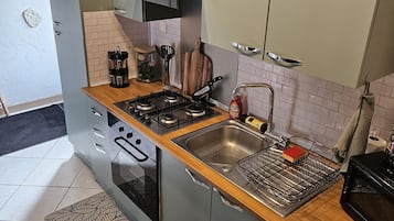 Ett kompakt kök med gasspis, diskho och inbyggd tvättmaskin.