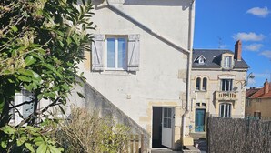 A two-story house with a small balcony and a door leading to the entrance. - Maison en Centre-ville Avec Jardin Privatif (Nevers)