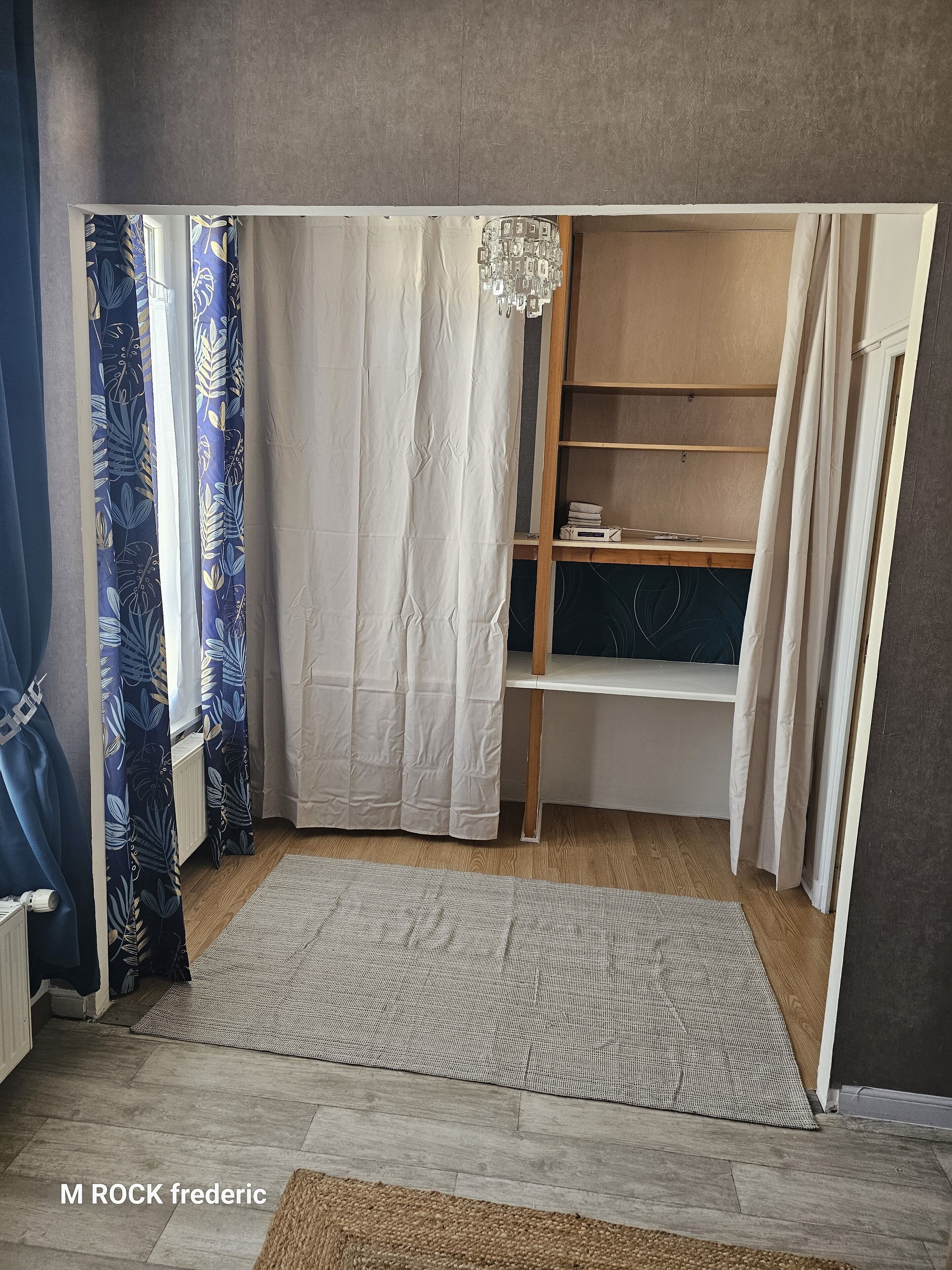 A room with a built-in wardrobe, a radiator, a wooden floor, and a patterned rug.