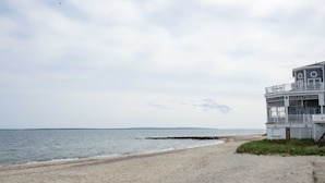 Een strand met een gebouw, voorzien van een balkon en een bordje dat aangeeft dat het een restaurant is.