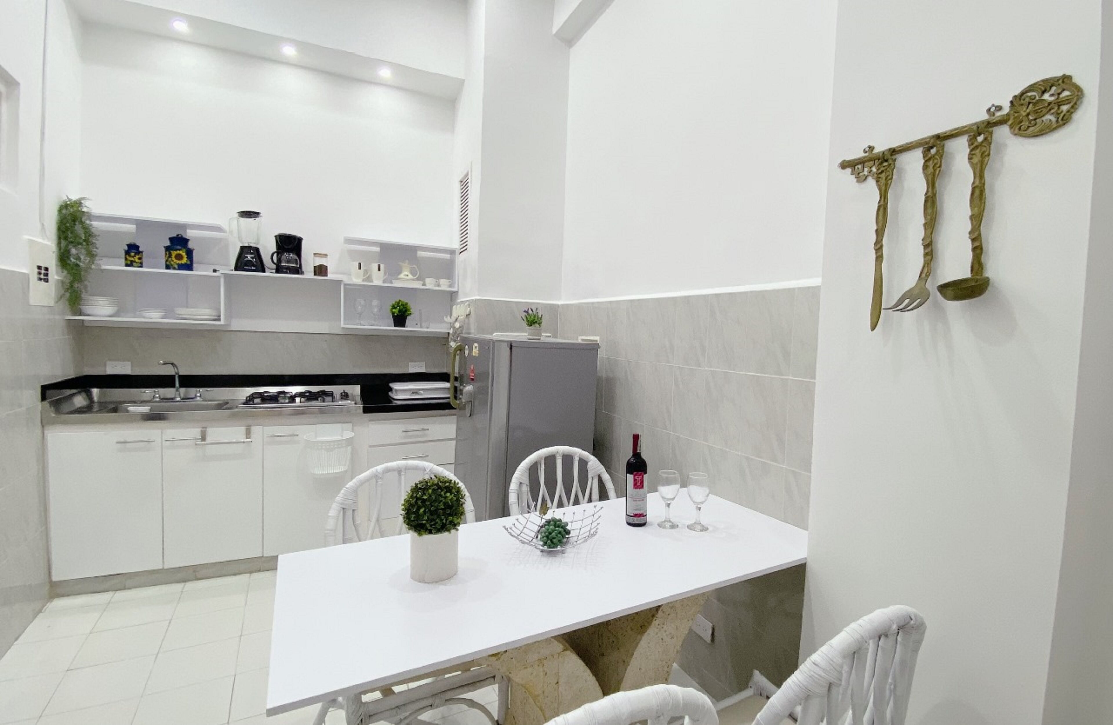 A modern kitchen with white cabinets, a dining table with chairs, and a wine bottle.