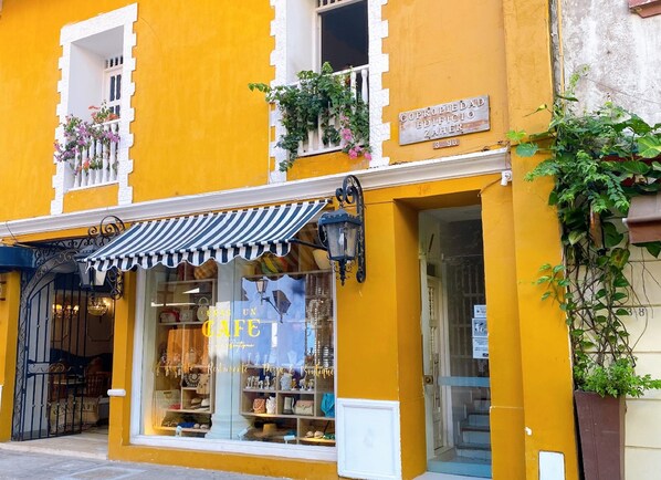A storefront with a striped awning, a sign reading "Café," and a window displaying various items.